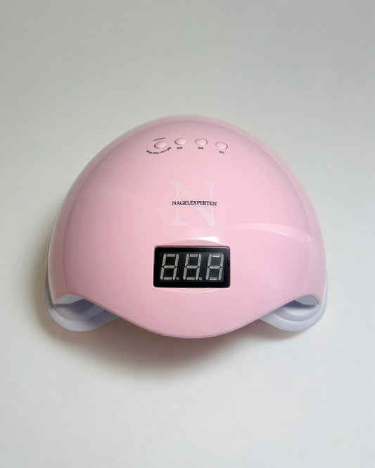 En rosa uv gel nagellampa med vit bakgrund för härdning av gellack och builder gel.